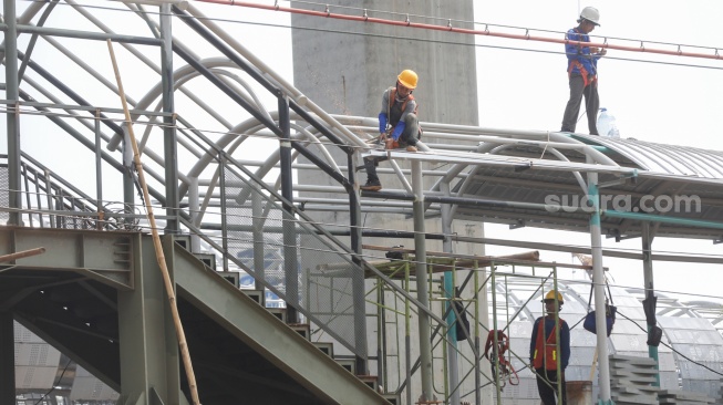 Kereta Rel Listrik (KRL) melintasi proyek pembangunan Stasiun Jakarta International Stadium (JIS) di kawasan Papanggo, Jakarta, Rabu (22/4/2026). [Suara.com/Alfian Winanto]
