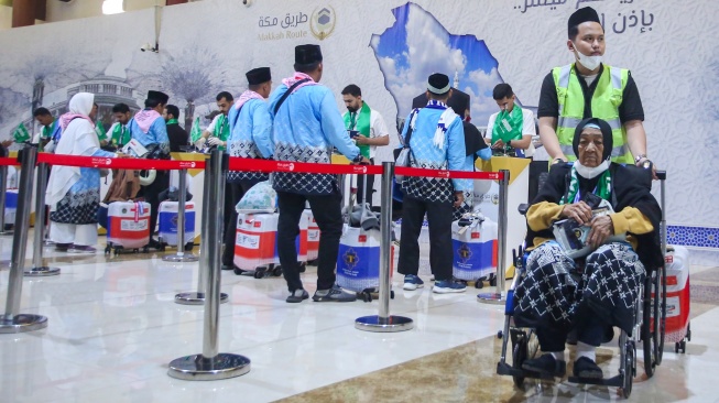 Petugas membantu calon haji berkebutuhan khusus berjalan menuju pesawat usai melapor diri di Makkah Route Terminal Haji dan Umrah 2F Bandara Soekarno Hatta, Tangerang, Banten, Rabu (22/4/2026). [ANTARA FOTO/Muhammad Iqbal/kye]