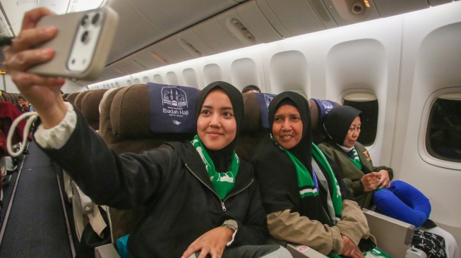 Jamaah calon haji melakukan swafoto di dalam pesawat Garuda Indonesia yang akan membawanya menuju tanah suci, di Terminal Haji dan Umrah 2F Bandara Soekarno Hatta, Tangerang, Banten, Rabu (22/4/2026). [ANTARA FOTO/Muhammad Iqbal/kye]