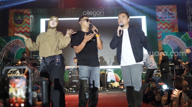 Denny Caknan bernyanyi di atas panggung bersama Wali Kota Cilegon, Robinsar dan sang istri, Alfi Rizki Aghnia di Alun-alun Cilegon, Senin 27 April 2026. [Hairul Alwan/Suara.com]