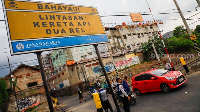 Pengendara melintasi rel perlintasan kereta api di dekat Stasiun Bekasi Timur, Bekasi, Jawa Barat, Rabu (30/4/2026). [Suara.com/Alfian Winanto]
