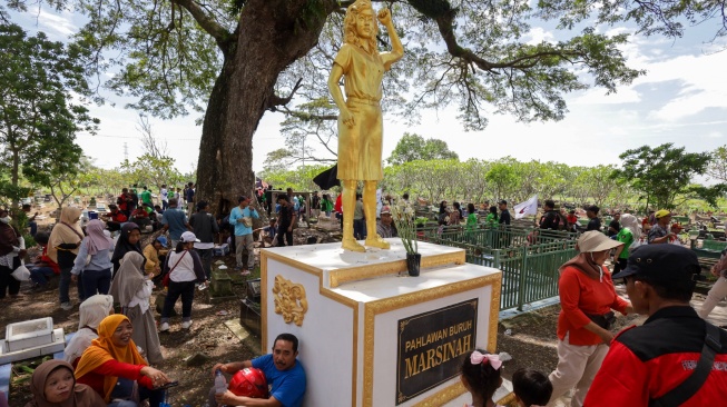 Sejumlah buruh beristirahat di dekat patung Marsinah saat ziarah makam pahlawan nasional Marsinah di Desa Nglundo, Kabupaten Nganjuk, Jawa Timur, Jumat (1/5/2026). [ANTARA FOTO/Prasetia Fauzani/nz]