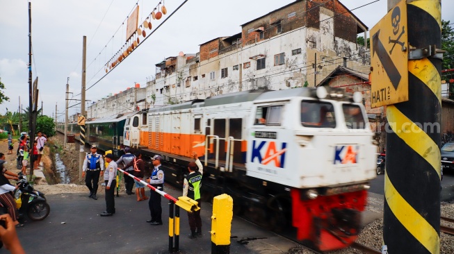 Pengendara berhentinsaat kereta melintas di perlintasan kereta api di dekat Stasiun Bekasi Timur, Bekasi, Jawa Barat, Rabu (30/4/2026). [Suara.com/Alfian Winanto]

