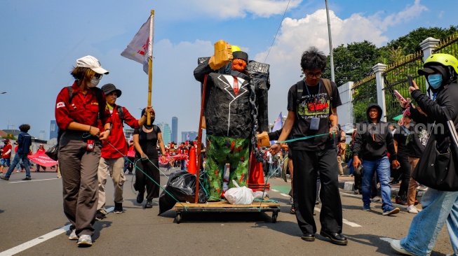 Masa dari berbagai elemen masalyarakat dan buruh membawa replika patung pejabat saat mengikuti aksi memperingati Hari Buruh Internasional atau May Day 2026 di depan gedung DPR RI, Jakarta, Jumat (1/5/2026). [Suara.com/Alfian Winanto]
