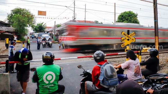Pengendara berhentinsaat kereta melintas di perlintasan kereta api di dekat Stasiun Bekasi Timur, Bekasi, Jawa Barat, Rabu (30/4/2026). [Suara.com/Alfian Winanto]
