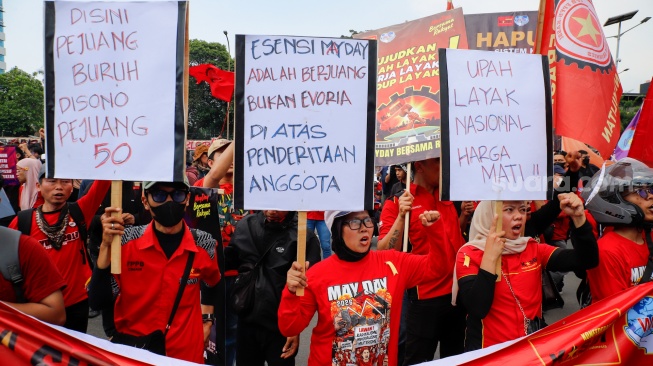 Massa dari berbagai elemen masyarakat dan buruh menempelkan poster pada aksi memperingati Hari Buruh Internasional atau May Day 2026 di depan gedung DPR RI, Jakarta, Jumat (1/5/2026). [Suara.com/Alfian Winanto]
