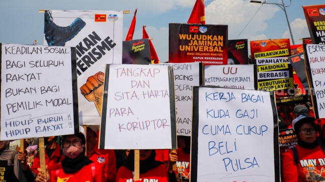 Massa dari berbagai elemen masyarakat dan buruh membawa poster pada aksi memperingati Hari Buruh Internasional atau May Day 2026 di depan gedung DPR RI, Jakarta, Jumat (1/5/2026). [Suara.com/Alfian Winanto]
