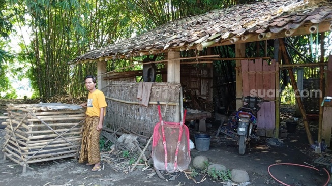 Nuryadin (40 tahun) berdiri di depan gubuk yang akan dijadikan pondok mengaji. (Suara.com/ Angga Haksoro Ardhi).   