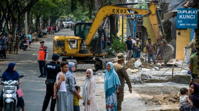 Warga menyaksikan petugas mengoperasikan alat berat saat pembongkaran bangunan liar di Pasar Kemis, Kabupaten Tangerang, Banten, Kamis (7/5/2026). [ANTARA FOTO/Putra M. Akbar/foc]