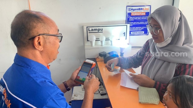Pemilik agen BRILink, Bambang Margono, saat melayani kosumen di tokonya. (Suara.com/Irwan Febri)