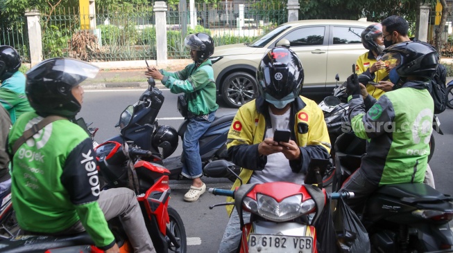 Pengemudi ojek online menunggu penumpang di seberang Stasiun Palmerah, Jakarta, Senin (11/5/2026). [Suara.com/Alfian Winanto]

