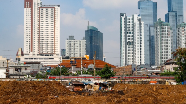 Suasana pemukiman penduduk dengan latar belakang gedung bertingkat di Jakarta, Selasa (12/5/2026). [Suara.com/Alfian Winanto]