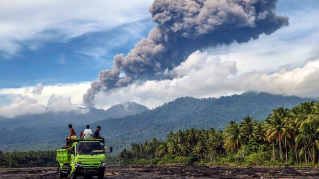 Warga melihat abu vulkanik keluar dari Gunung Dukono yang terlihat di area bekas banjir lahar dingin Desa Mamuya, Kecamatan Galela, Maluku Utara, Selasa (12/5/2026). [ANTARA FOTO/Andri Saputra/sgd]