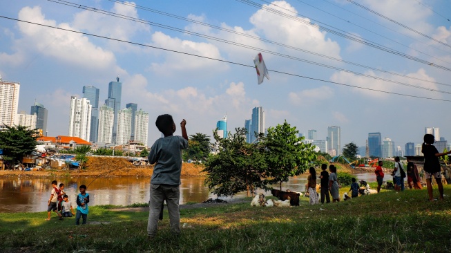 Warga beraktivitas dengan latar belakang gedung bertingkat di Jakarta, Selasa (12/5/2026). [Suara.com/Alfian Winanto]