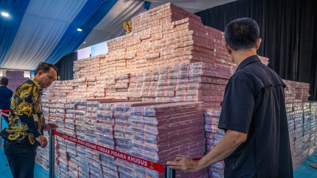 Petugas memasang garis penghalang pada tumpukan uang saat kegiatan penyerahan denda administratif dan lahan kawasan hutan di Kejaksaan Agung, Jakarta, Rabu (13/5/2026). [ANTARA FOTO/Bayu Pratama S/tom]