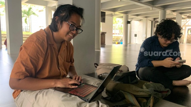 Mahasiswa Teknik Kimia UGM, Khaizuran Delwyn, ketika mengerjakan tugas di Masjid Al-Mustadam. (Suara.com/Irwan Febri)