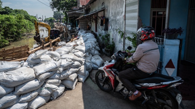 Pengendara sepeda motor melihat pekerja Dinas Pekerjaan Umum Kota Semarang memperbaiki struktur Jalan Jembawan 1 yang amblas di kawasan Kalibanteng Kulon, Semarang, Jawa Tengah, Senin (18/5/2026). [ANTARA FOTO/Aprillio Akbar/bar]