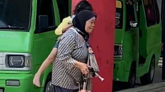 Mak Yati dengan sabar dan kasih sayangnya menggendong Ainsa sambil berdagang asongan. Anisa adalah bocah difabel yang diasuh dari usia lima hari, karena sang anak sudah dibuang orangtuanya sejak masih bayi. [Instagram]