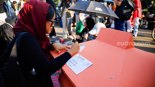 Pegiat HAM yang tergabung dalam Jaringan Solidaritas Korban menulis pesan perubahan saat mengikuti aksi kamisan ke-908 di seberang Istana Merdeka, Jakarta, Kamis (21/5/2026). [Suara.com/Alfian Winanto]
