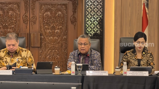 (Kiri-Kanan) Menko Perekonomian Airlangga Hartarto, Gubernur Bank Indonesia Perry Warjiyo, dan Ketua DK OJK Friderica Widyasari Dewi dalam acara Sosialisasi Tata Kelola Ekspor SDA Strategis dan Implementasi Peraturan Pemerintah tentang DHE yang digelar di Kantor Kemenko Perekonomian, Jakarta, Kamis (21/5/2026). [Suara.com/Dicky Prastya]
