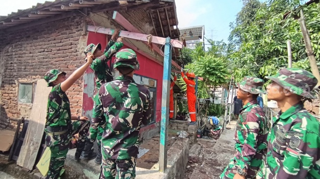 Sejumlah prejurit TNI Kodim 0623/Cilegon bersama perwakilan industri di Cilegon membongkar sasaran rumah tidak layak huni di Kota Cilegon, Banten. [Hairul Alwan/Suara.com]