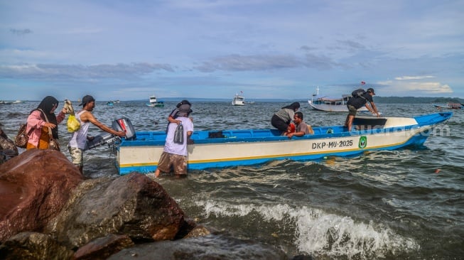 Warga naik ke dalam perahu motor yang bersandar di tepi bebatuan Pantai Labuha, Pulau Bacan, Kabupaten Halmahera Selatan, Maluku Utara, Selasa (26/5/2026). [ANTARA FOTO/Andri Saputra/agr]