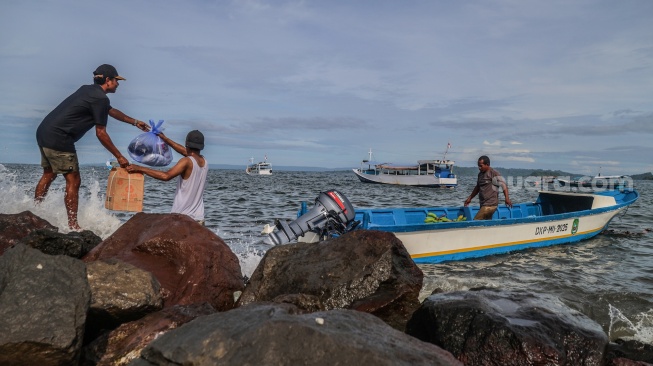 Warga mengangkut barang ke dalam perahu motor yang bersandar di tepi bebatuan Pantai Labuha, Pulau Bacan, Kabupaten Halmahera Selatan, Maluku Utara, Selasa (26/5/2026). [ANTARA FOTO/Andri Saputra/agr]