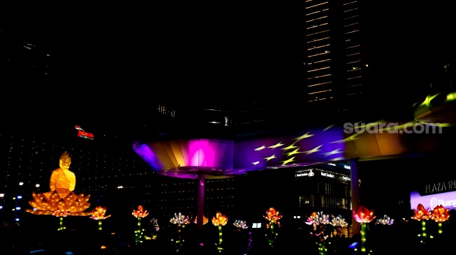 Warga melihat ornamen lampu hias saat llumination of Jakarta: Glow of Peace di kawasan Bundaran HI, Jakarta, Jumat (29/5/2026). [Suara.com/Alfian Winanto]