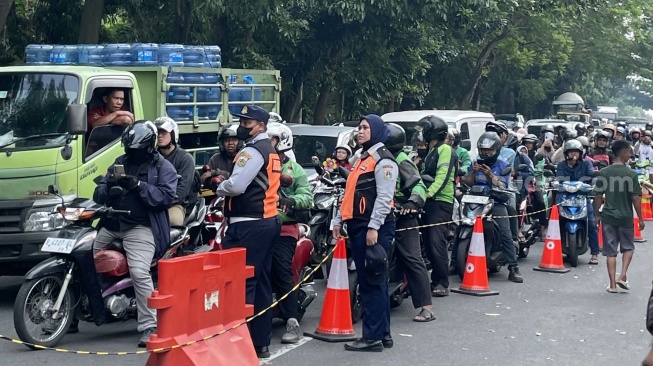 Sebuah truk milik Dinas Sumber Daya Air (SDA) DKI Jakarta yang tengah mengangkut muatan tanah untuk menimbun jalan amblas justru ikut terjeblos di lokasi kejadian dekat KFC Lenteng Agung, Jakarta Selatan, Jumat (29/5/2026). (Suara.com/Adiyoga)