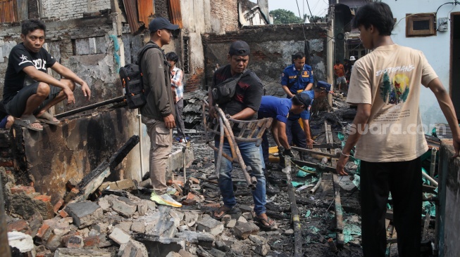 Warga mencari barang di rumahnya yang telah terbakar di kawasan Kebon Kosong, Kemayoran, Jakarta, Selasa (2/6/2026). [Suara.com/Alfian Winanto]
