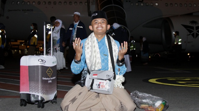 Seorang haji dari kelompok terbang (kloter) pertama memanjatkan doa syukur saat tiba di Bandara Internasional Juanda, Sidoarjo, Jawa Timur, Senin (1/6/2026). [ANTARA FOTO/Umarul Faruq/kye]