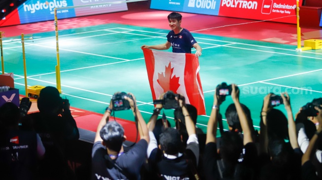 Pebulu tangkis tunggal putra Kanada Victor Lai berpose dengan bendera negaranya usai mengalahkan tunggal putra Indonesia Jonatan Christie pada final Polytron Indonesia Open 2026 di Istora Senayan, Jakarta, Minggu (7/6/2026). [Suara.com/Alfian Winanto]
