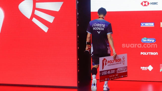 Pebulu tangkis tunggal putra Indonesia Jonatan Christie berjalan kebalik panggung podium dengan pialanya usai dikalahkan Pebulu Tangkis tunggal putra Kanada Victor Lai pada pertandingan final Polytron Indonesia Open 2026 di Istora Senayan, Jakarta, Minggu (7/6/2026). [Suara.com/Alfian Winanto]