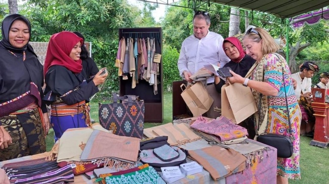 Nisa menyambut wisatawan asal Australia yang berkunjung ke Lombok membeli kain tenun buatannya (Dok. Nisa)