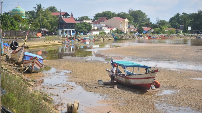 Nelayan memperbaiki perahunya di atas sungai yang mengalami pendangkalan di banjir kanal Air Tawar, Padang, Sumatera Barat, Senin (15/6/2026). [ANTARA FOTO/Fitra Yogi/bar]