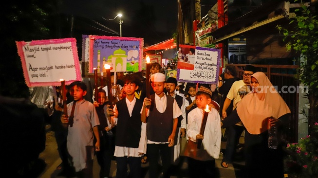 Sejumlah warga dan anak-anak mengikuti pawai obor di Kawasan Menteng, Jakarta Pusat, Senin (15/6/2026).  [Suara.com/Alfian Winanto]