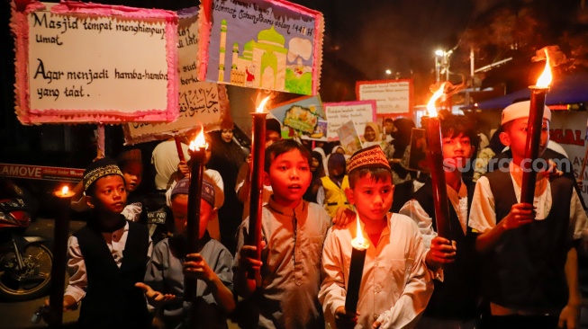 Sejumlah warga dan anak-anak mengikuti pawai obor di Kawasan Menteng, Jakarta Pusat, Senin (15/6/2026).  [Suara.com/Alfian Winanto]