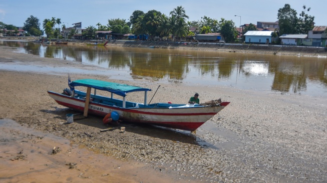 Nelayan memperbaiki perahunya di atas sungai yang mengalami pendangkalan di banjir kanal Air Tawar, Padang, Sumatera Barat, Senin (15/6/2026). [ANTARA FOTO/Fitra Yogi/bar]