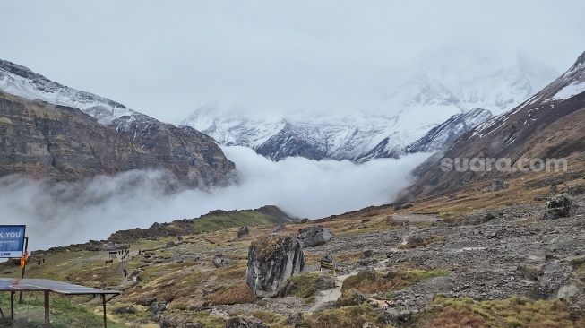 Kabut tebal memadati celah lembah di antara tebing batu dan puncak bersalju di sepanjang jalur pendakian menuju Annapurna Base Camp, Nepal, Jumat (29/5/2026). [Suara.com/Rizka Chaerani] 