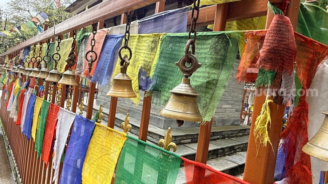 Deretan lonceng kuningan dan bendera doa khas Tibet menghiasi salah satu sudut tempat suci di jalur pendakian menuju kawasan Himalaya, Nepal, Selasa (26/5/2026). [Suara.com/Rizka Chaerani]