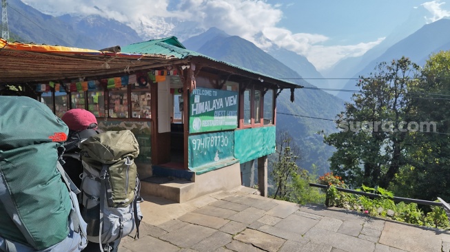 Pendaki melintas di depan penginapan Himalaya View Guest House di jalur trekking Annapurna Base Camp, Nepal, Selasa (26/5/2026). [Suara.com/Rizka Chaerani]