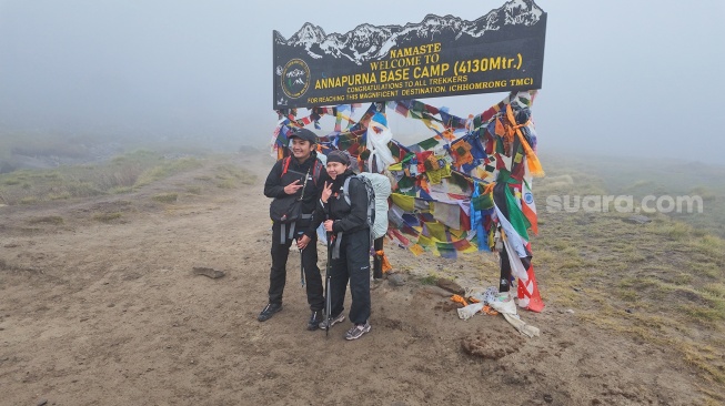 Pendaki berfoto di depan penanda Annapurna Base Camp (4.130 mdpl), Nepal, setelah menyelesaikan perjalanan trekking di kawasan Pegunungan Himalaya, Kamis (28/5/2026). [Suara.com/Rizka Chaerani] 