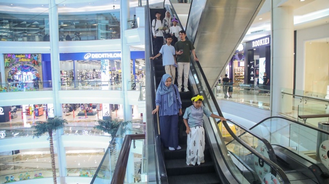 Orang tua bersama anaknya menuruni eskalator usai mengikuti proses sunat massal di Mal Kota Kasablanka, Jakarta, Selasa (16/6/2026). [Suara.com/Alfian Winanto]