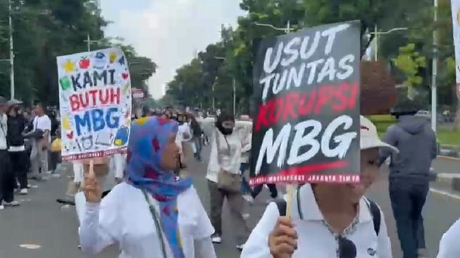 Peserta aksi demo di kawasan Patung Kuda, Jakarta Pusat membentangkan poster berisi dukungan terhadap program MBG. [Suara.com/Adiyoga]