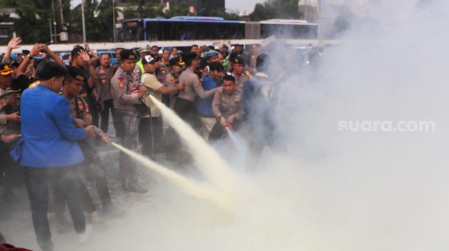 Petugas memadamkan api dengan apar saat sejumlah Mahasiswa melakukan aksi di depan gedung DPR RI, Jakarta, Senin (22/6/2026). [Suara.com/Alfian Winanto]
