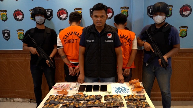 Anngota Ditres Narkoba Polda Metro Jaya bersama tersangka dan barang bukti kasus penyelundupan narkotika jenis etomidate dan ekstasi yang disembunyikan di dalam kemasan beras Basmati asal India. [istimewa]