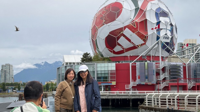 Warga berfoto dengan latar belakang instalasi raksasa berbentuk bola resmi Piala Dunia 2026 yang menghiasi gedung Science World di Vancouver, Kanada, Kamis (25/6/2026). [ANTARA FOTO/Arif Prada/app/foc]
