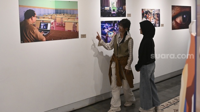 Pengunjung melihat karya foto saat pameran foto bertajuk Perisai Tunas di ANTARA Heritage Center, Jakarta, Kamis (25/6/2026). [Suara.com/Alfian Winanto]