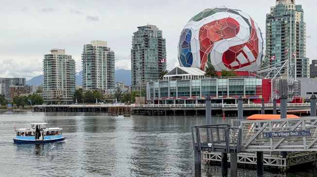 Sebuah perahu wisata melintasi instalasi raksasa berbentuk bola resmi Piala Dunia 2026 yang menghiasi gedung Science World di kawasan False Creek, Vancouver, Kanada, Kamis (25/6/2026). [ANTARA FOTO/Arif Prada/app/foc]
