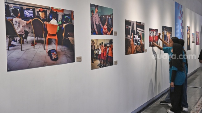 Pengunjung melihat karya foto saat pameran foto bertajuk Perisai Tunas di ANTARA Heritage Center, Jakarta, Kamis (25/6/2026). [Suara.com/Alfian Winanto]
